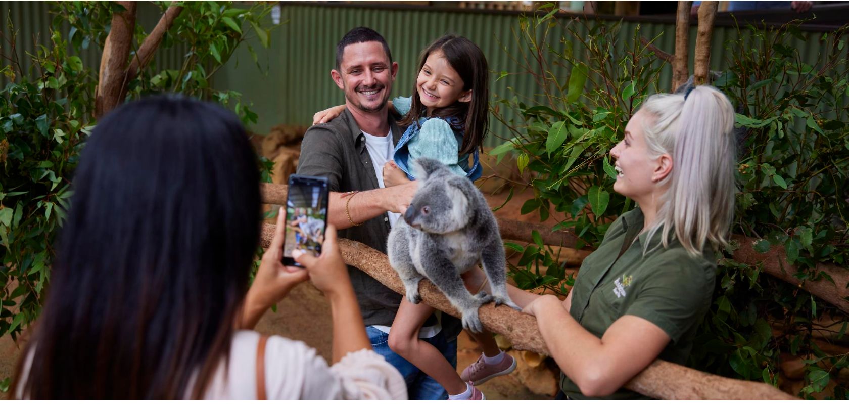 A Group Of People Holding A Koala Bear