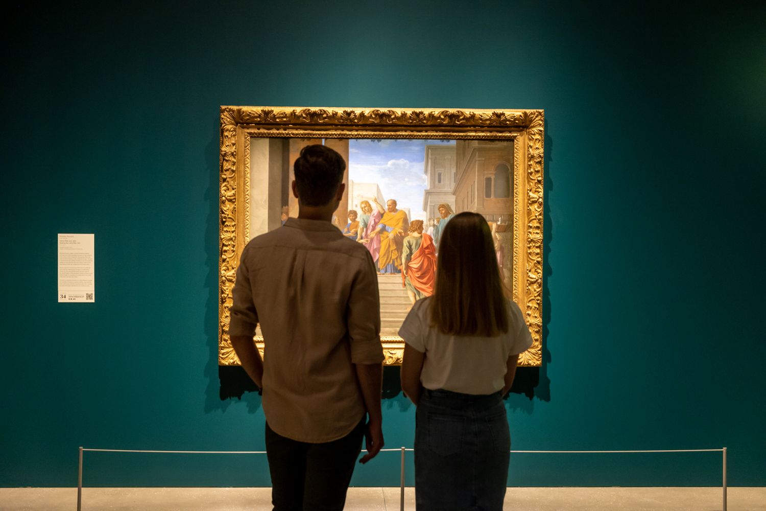 A Man And A Woman Looking At A Painting On A Wall