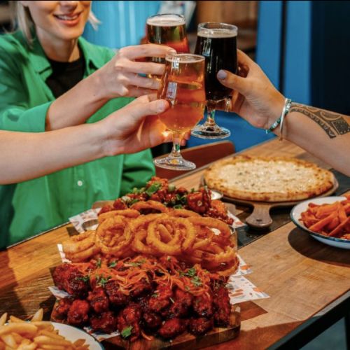 A Person Holding A Glass Of Beer at BrewDog DogTap BrisbaneAnd A Plate Of Food