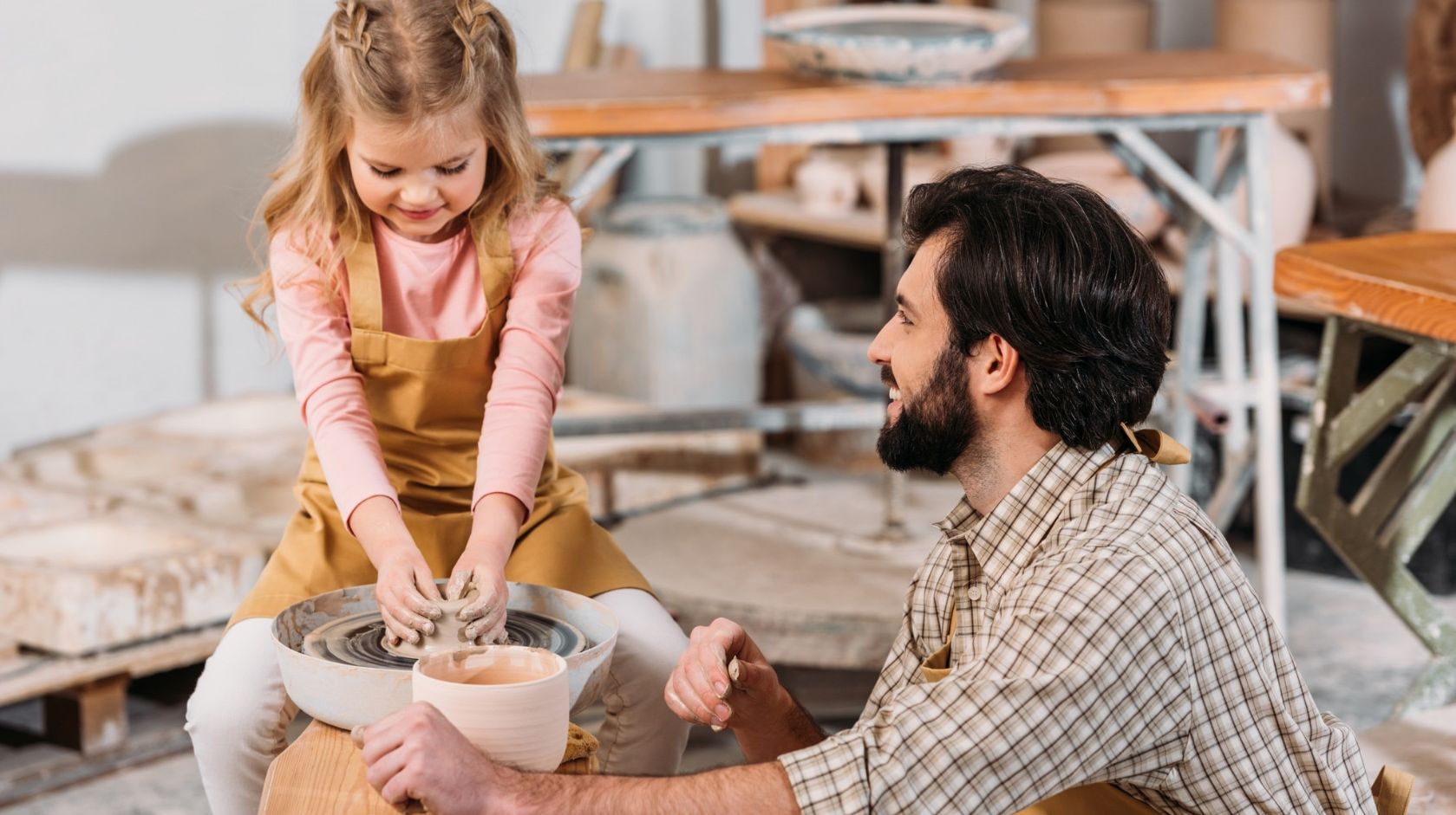 A Person And A Girl Sitting in a pottery class