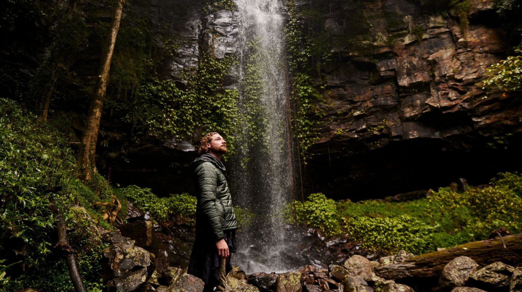 A Man Standing In Front Of A Waterfall