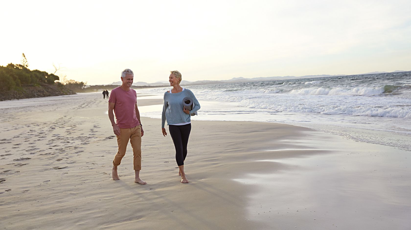 A Man And Woman Walking On Belongil Beach