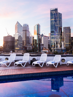 A Group Of Chairs By A Pool With A City Skyline In The Background