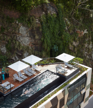 A Building With A Pool And A Mountain In The Background